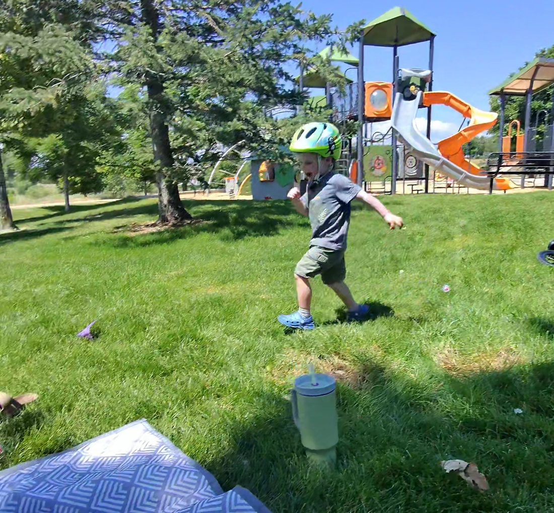 A child running across the grass at a neighborhood park